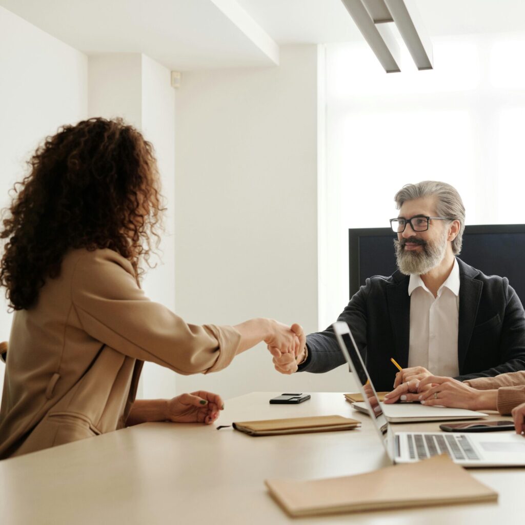 Colleagues in an office celebrating a successful negotiation with a handshake.